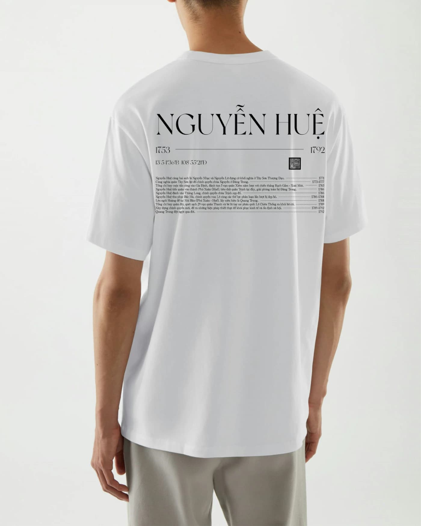 A relaxed white tee seen from behind, a small block of type printed high across the back.