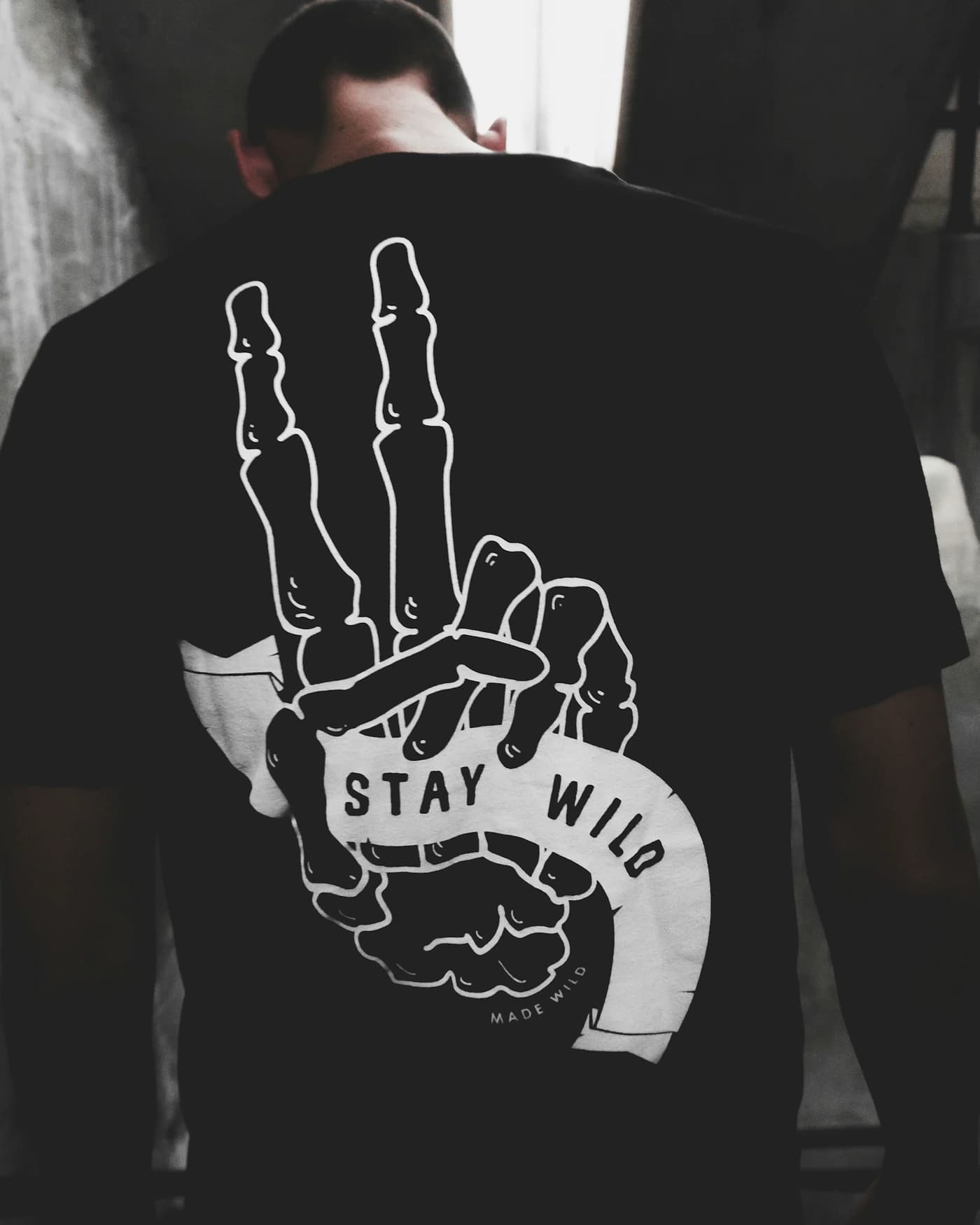 A black tee worn from behind, a large line-drawn graphic filling the whole of the back panel.