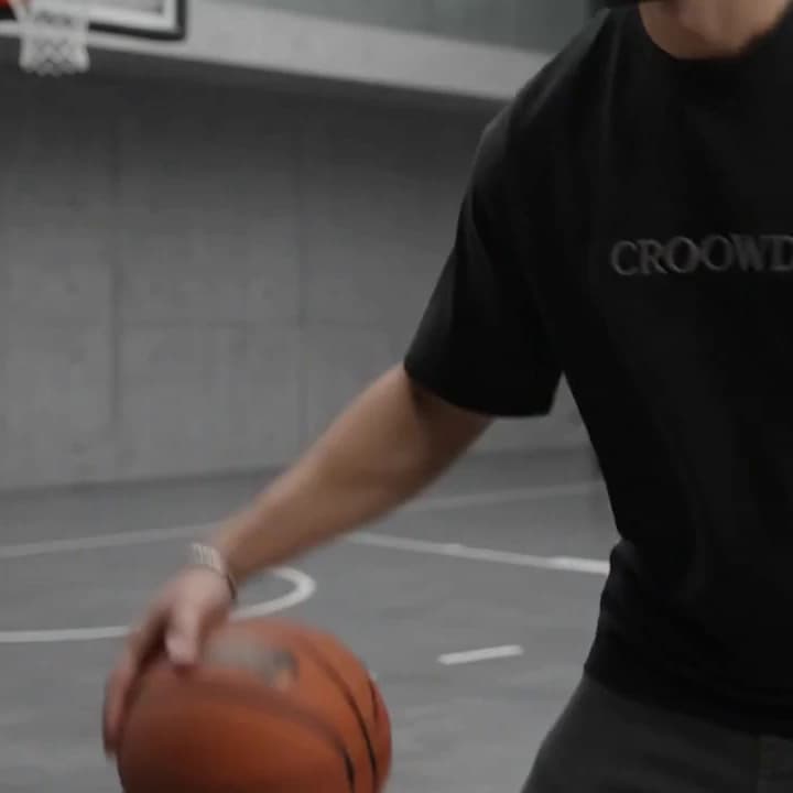 An oversized black tee with a small CROOWDIO chest print, a basketball held at the hip.