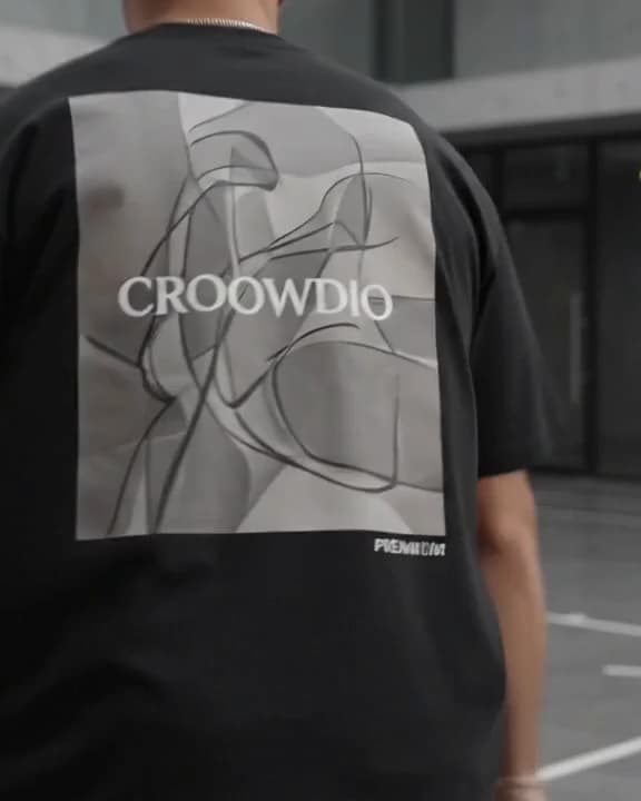 The back of a black tee, filled by a pale panel of loose line drawing with CROOWDIO set across it.